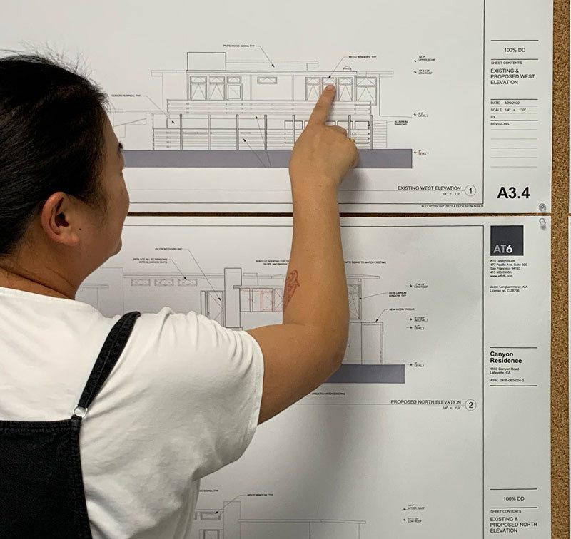 woman pointing to architectural drawings on a wall