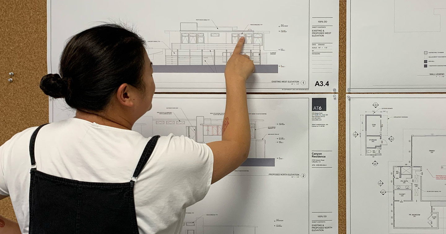woman pointing to architectural drawings on a wall