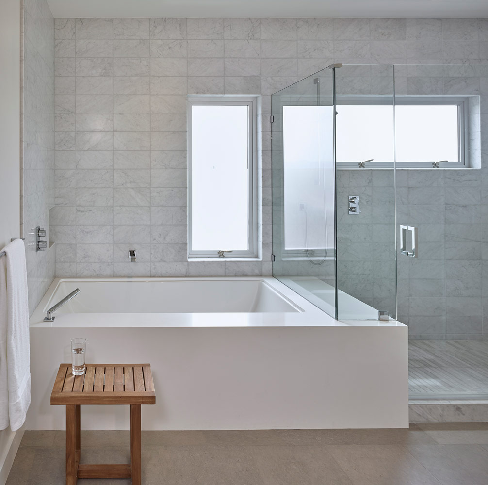 modern bathtub in bathroom with custom-cut Carrera marble tiles