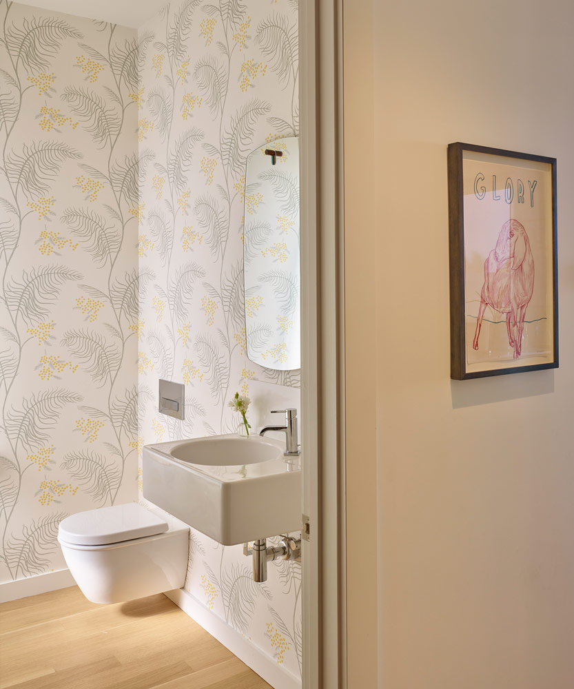 modern bathroom with yellow and grey floral wallpaper and wall mounted toilet