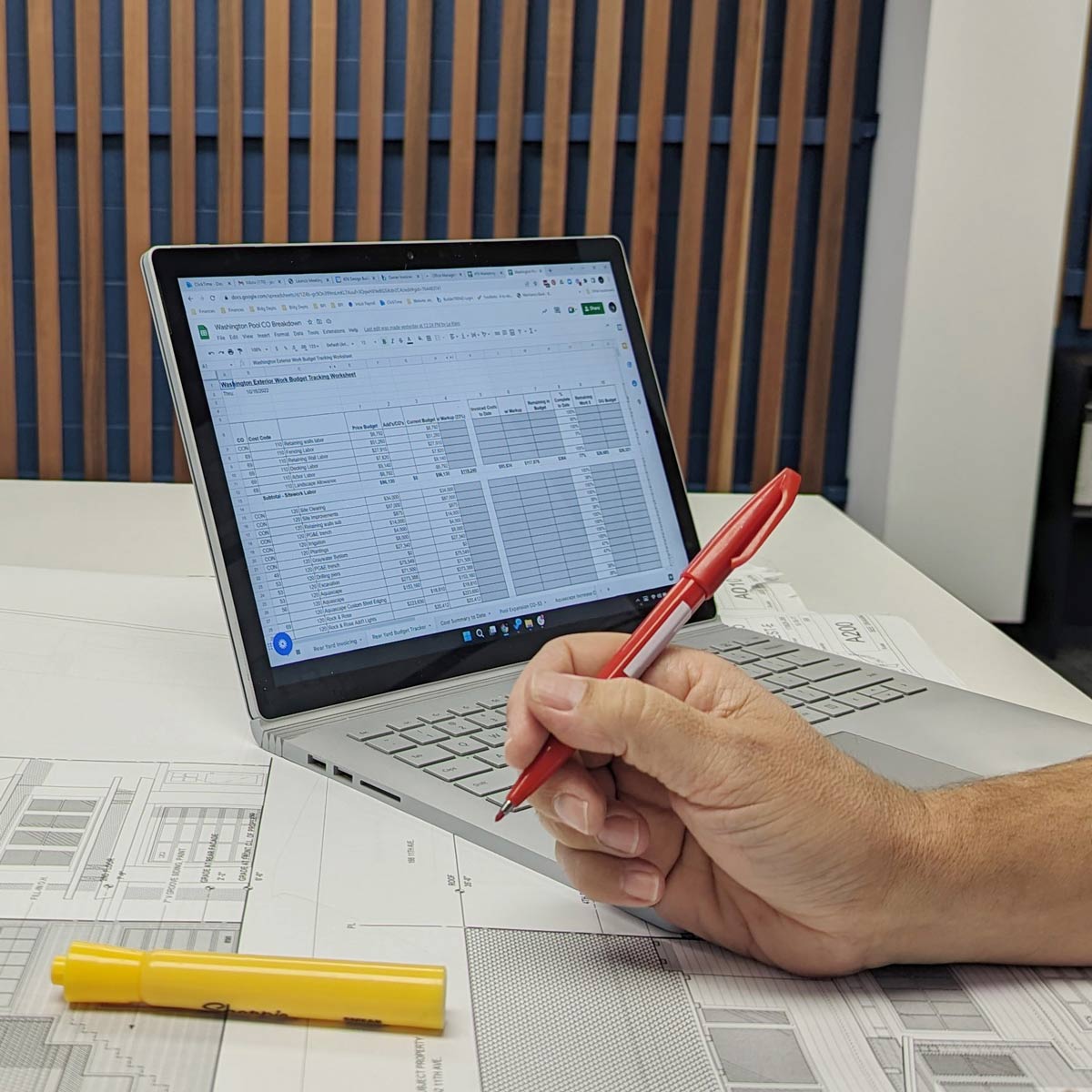 man writing with laptop showing spreadsheets