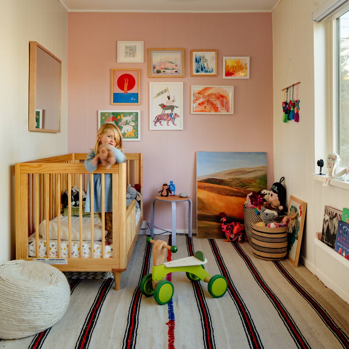 Small child standing in her cot in pink bedroom