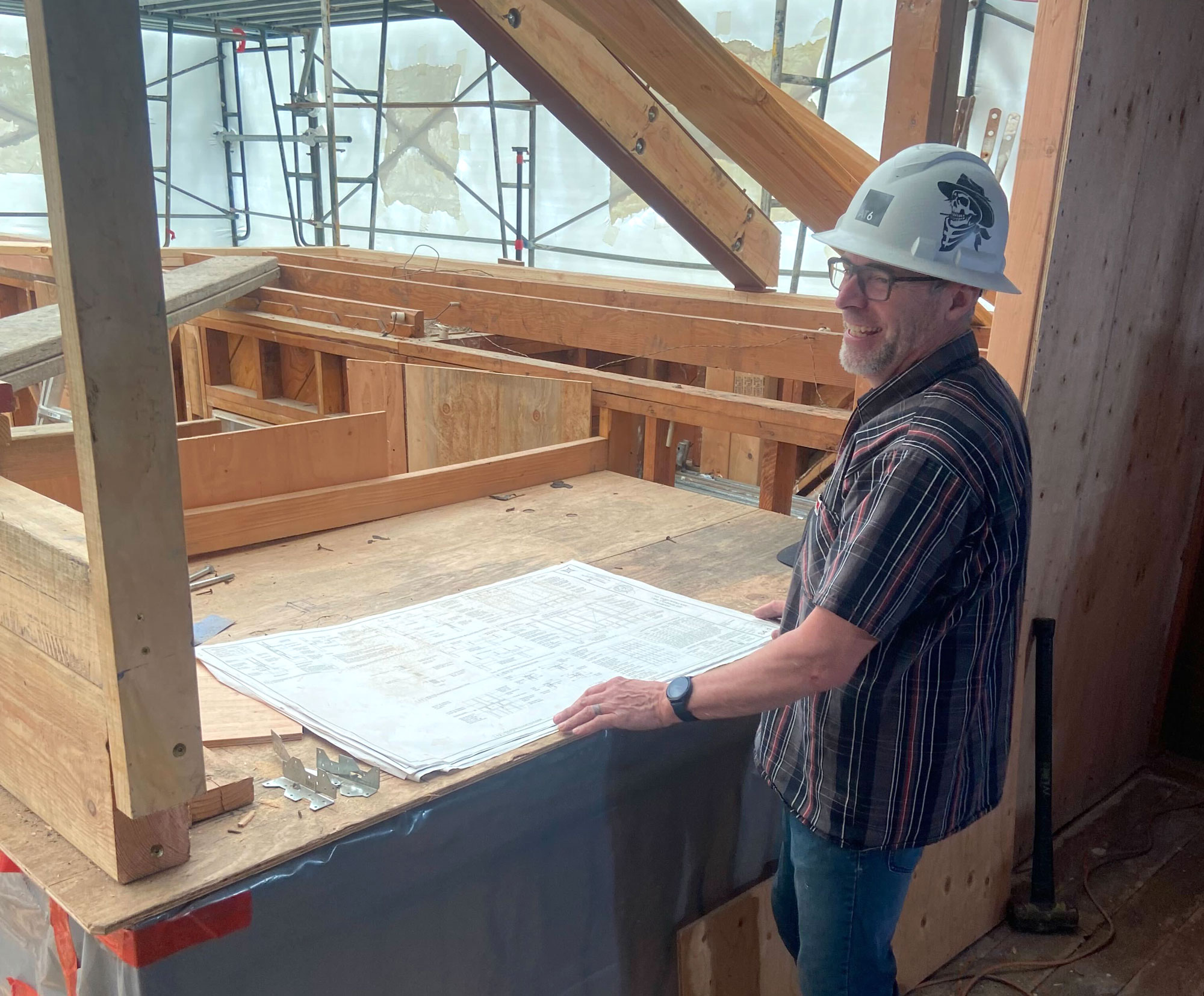 Brad with hard hat and construction drawings on site