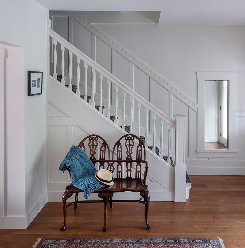 Renovation with wood floor entryway white staircase and antique bench