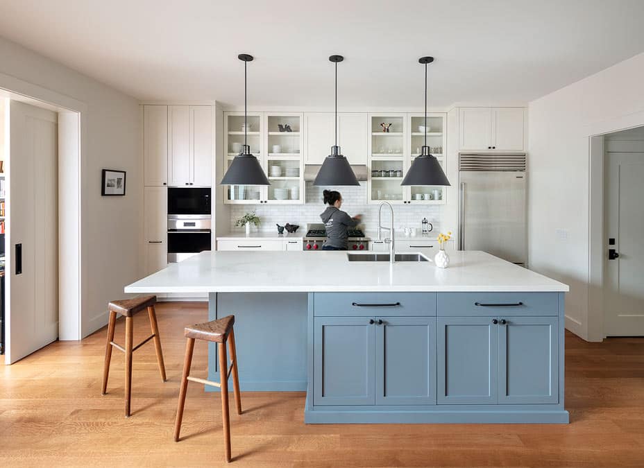 modern open plan kitchen with blue grey cabinets with white countertop and black pendants in San Francisco renovation