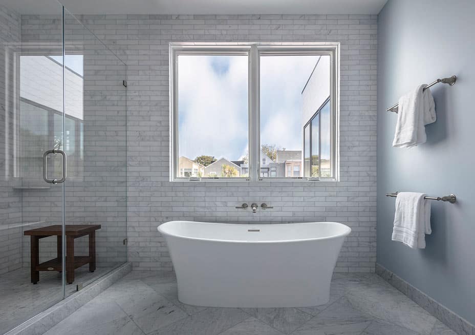 Blue and white and grey bathroom with modern bathtub and large window in san francisco renovation