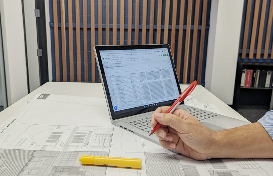 Man's hand with pen and laptop in background