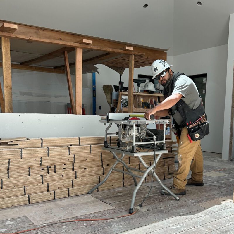 Carlos working on construction site with hard hat, protective eyewear and tool belt