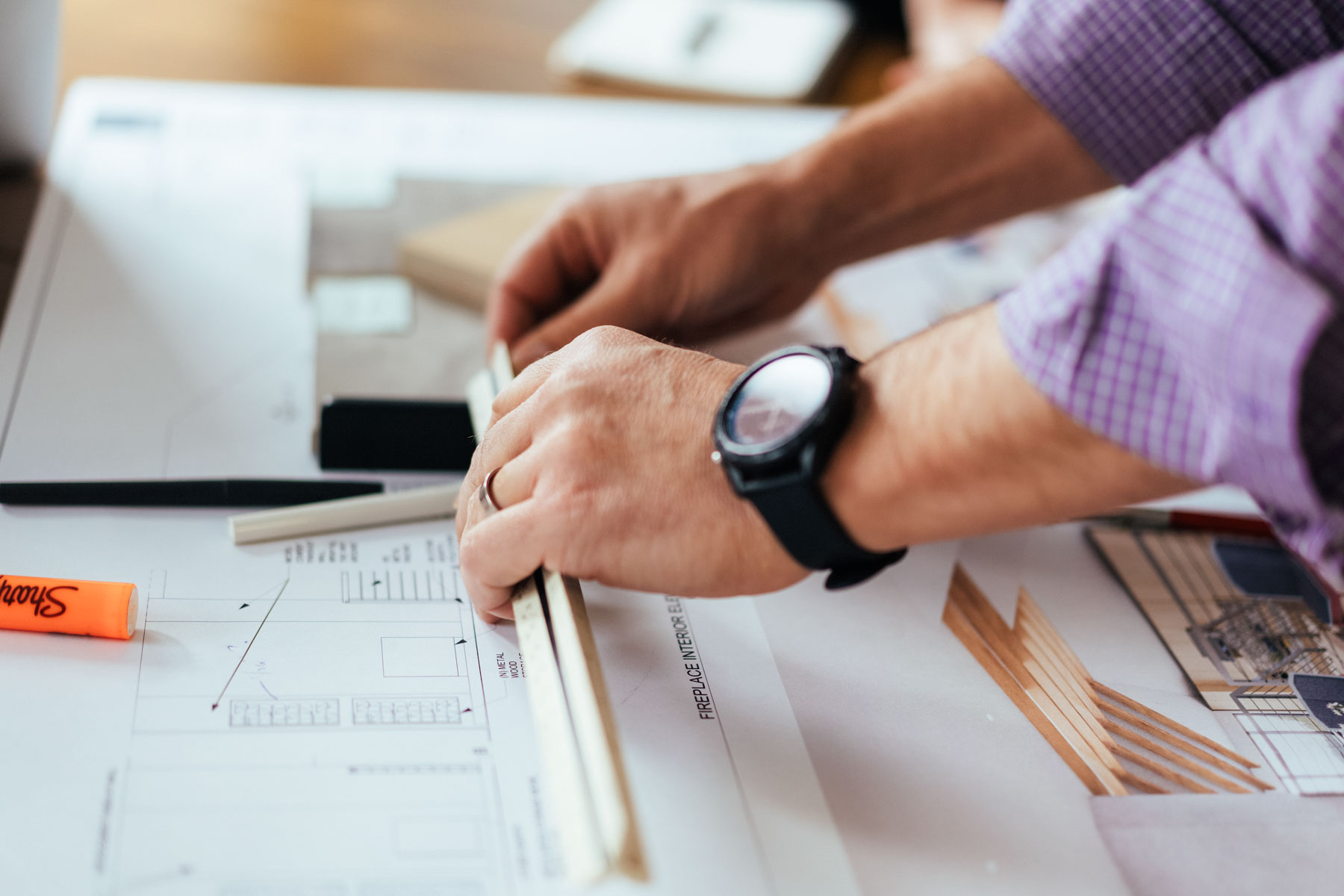 hands holding ruler on construction drawings