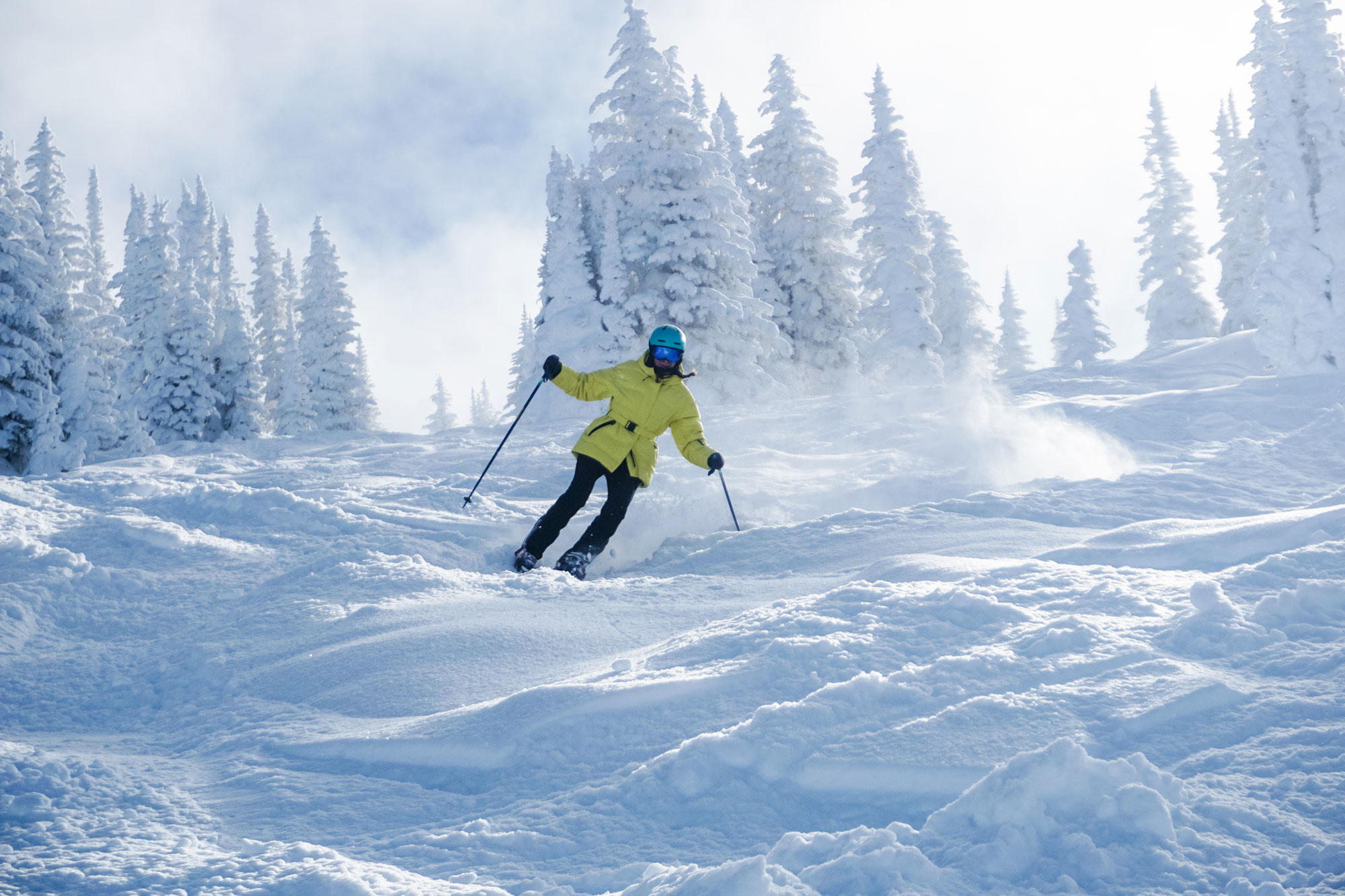 woman in yellow jacket skiing down slope