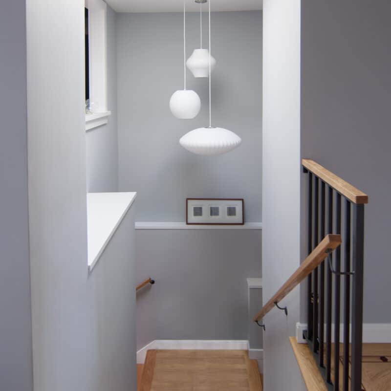 Modern stairwell showcases the skylight sending light which highlights a modern trio of lamps. Bay area.